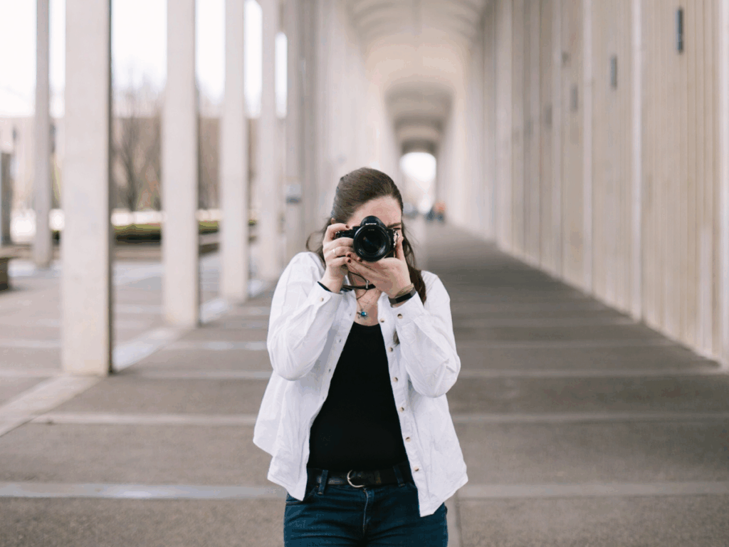 Photographer with a camera pointing in the direction of the viewer
