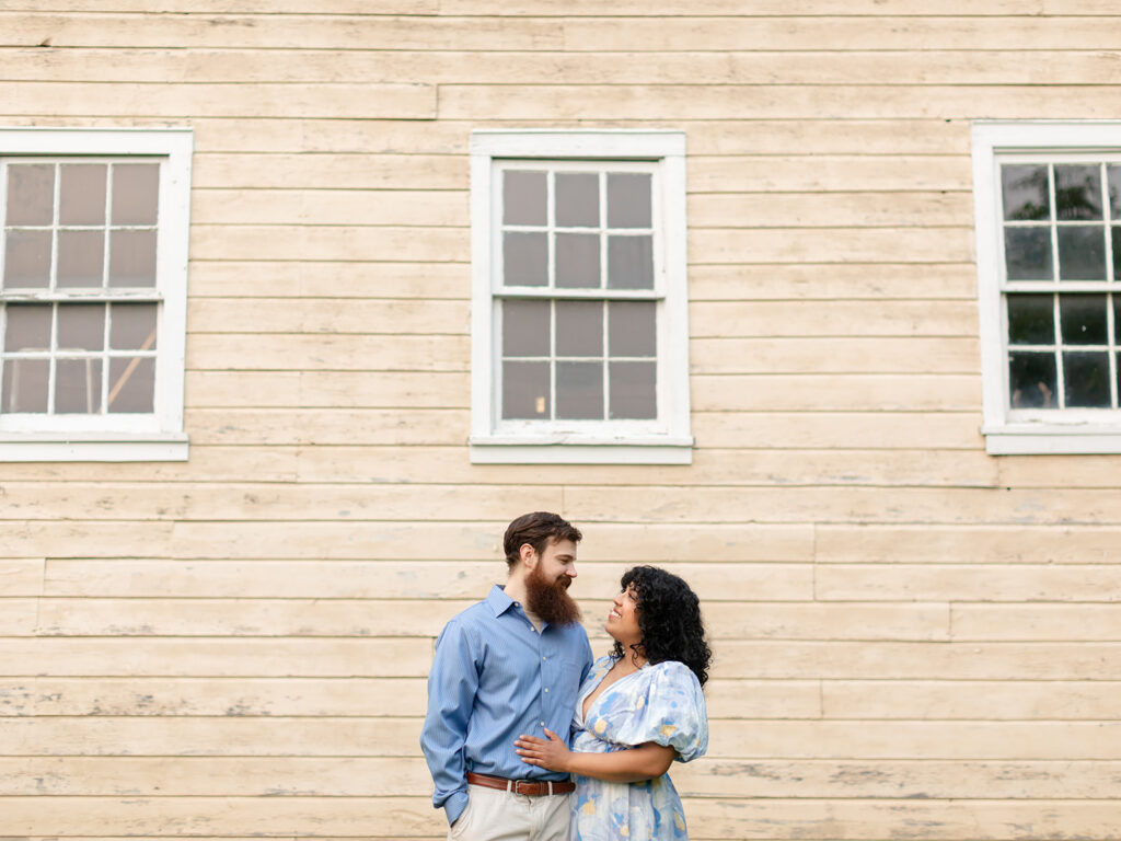 Dressed up couple in front of a rustic tan barn
