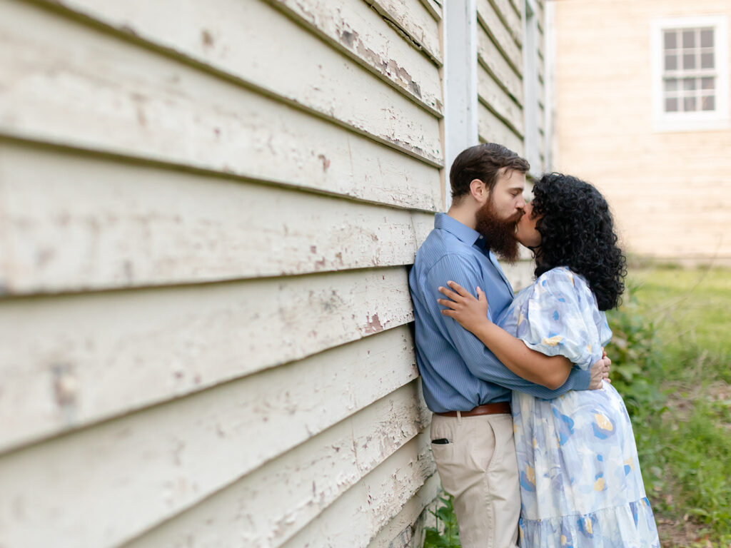 Couple kissing on the side of the rustic, weathered barn