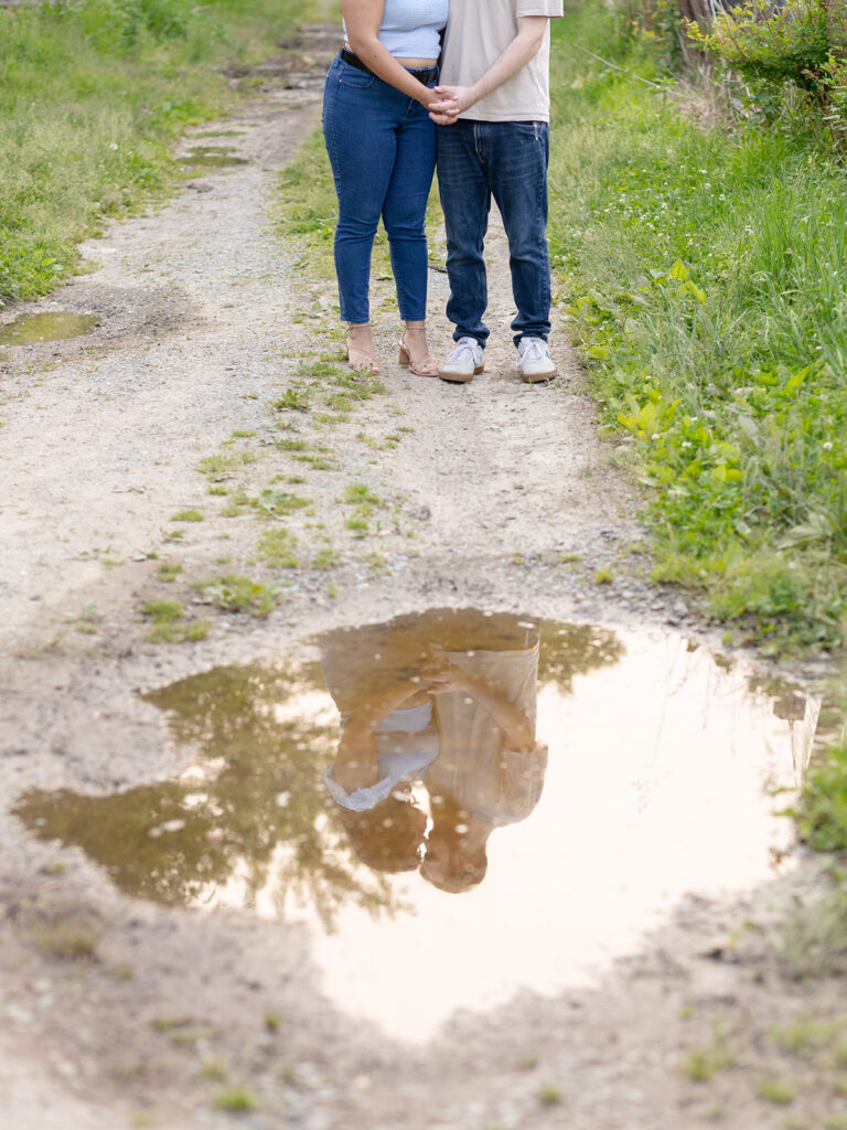 Reflection of a couple posing within a muddy puddle