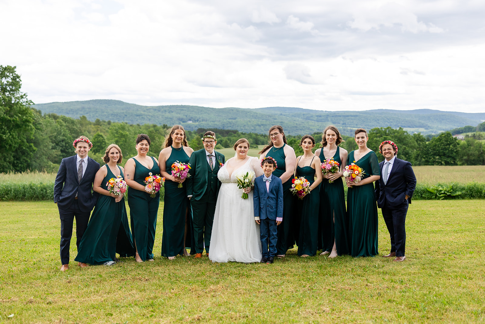 Group of wedding people in a field with a mountainous backdrop